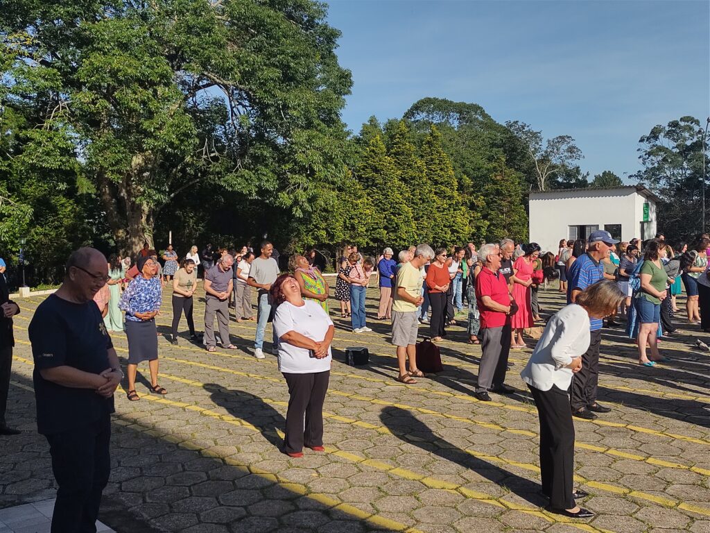 imagem dos participantes em filas, no pátio das bandeiraas da academia de ibiuna todos sorrindo durante o treino do riso