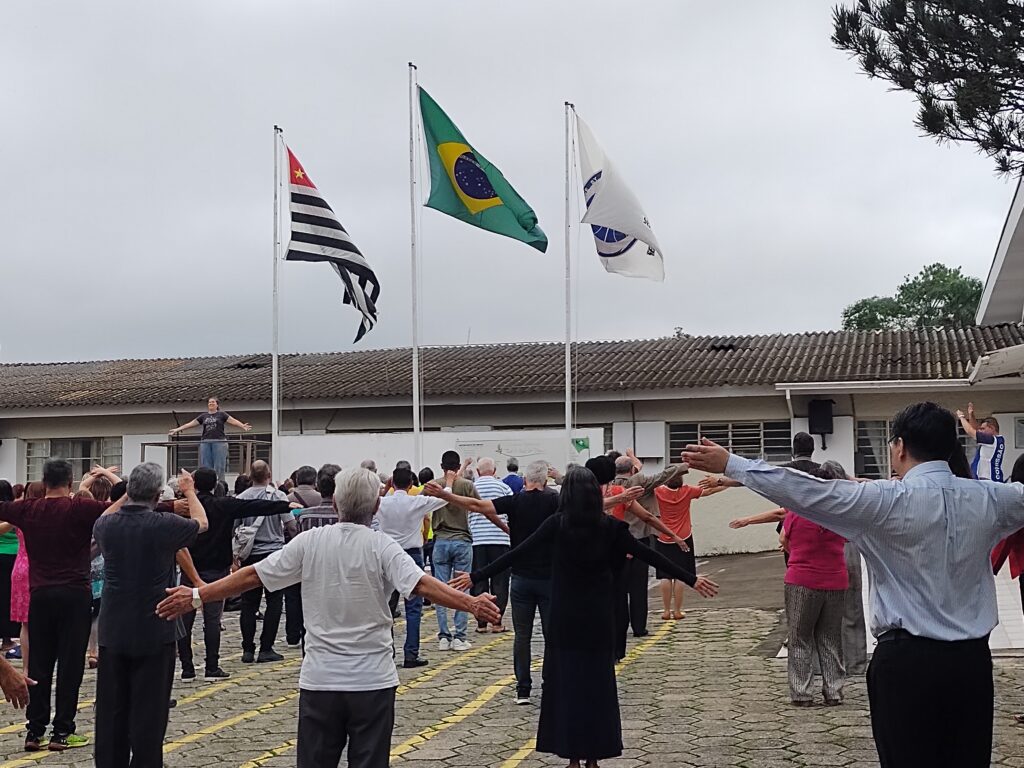 fotos dos participantes enfileirados no pátio das bandeiras da academia fazendo a ginástica matinal